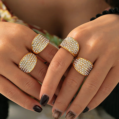 Hands wearing multiple gold full pave concave dome rings