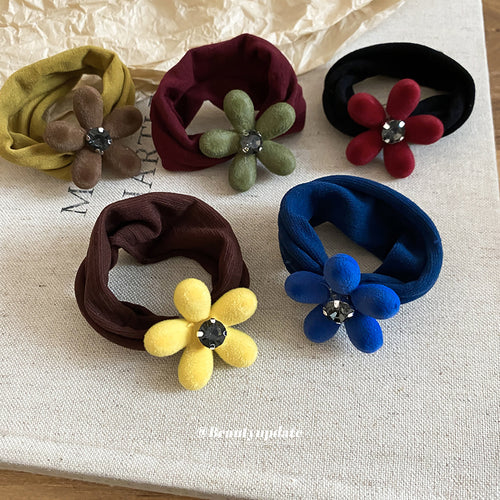 Five velvet flower scrunchies laid on light fabric