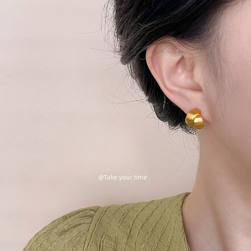 Brushed chunky C-shaped stud earrings shown worn on an ear.