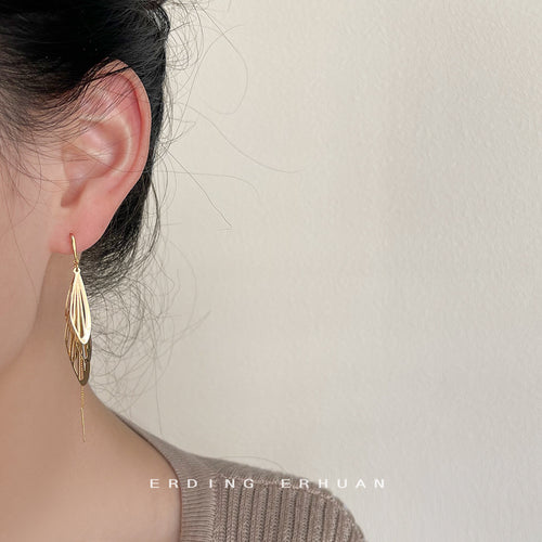 Gold wing chain drop earring worn on ear side profile