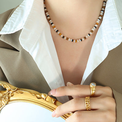 Model wearing multicolor disc bead necklace with white shirt and taupe blazer