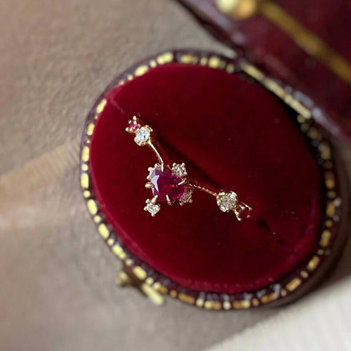 Gold heart ruby ring resting in open red velvet jewelry box