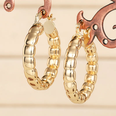 gold tone earrings showing round hoops with repeating raised link-like sections