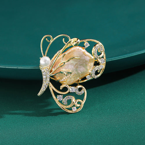 Front view of an openwork gold-tone butterfly with an irregular shell center and pearls
