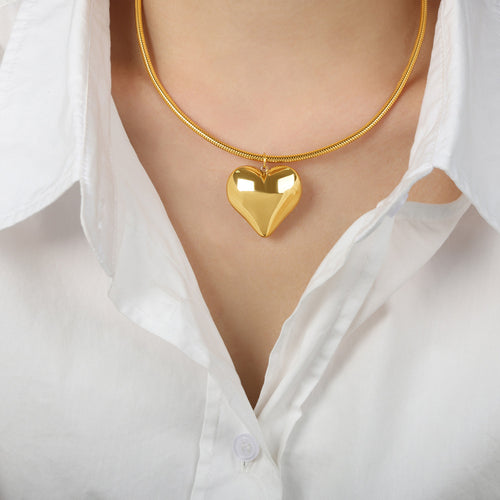 Model in white shirt wearing gold puffy heart snake chain necklace