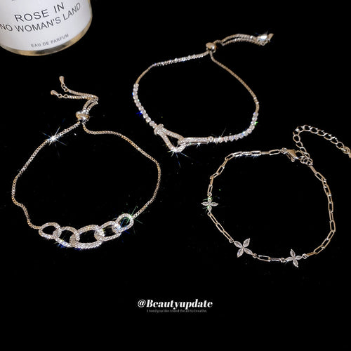Three silver crystal bracelets displayed flat on black background