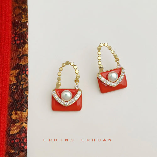Orange enamel handbag pearl crystal earrings on white with red cloth