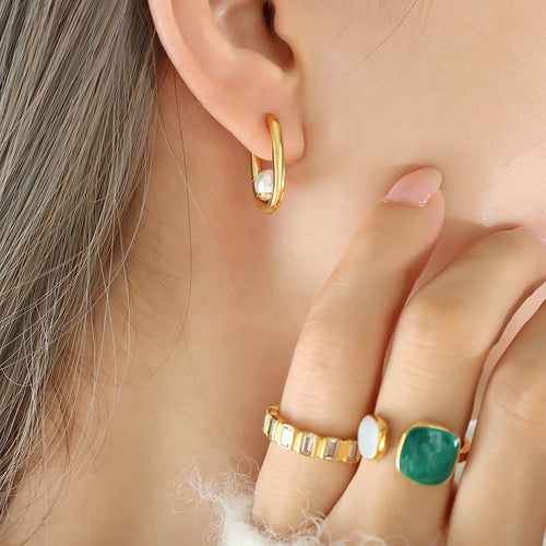 Gold U-hoop earring with white pearl bead worn on ear