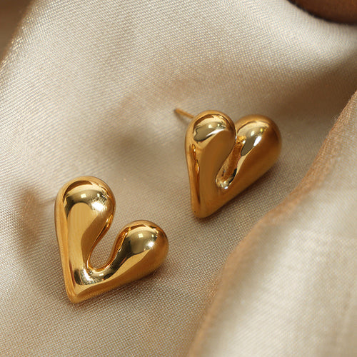 Pair of gold solid heart studs on satin fabric