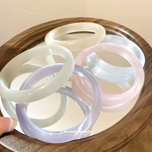 Assorted pastel cat eye round bangles piled on round wooden tray