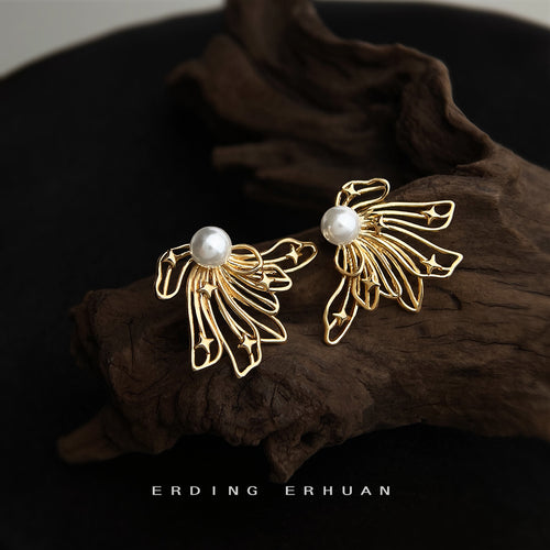 Gold openwork butterfly wing pearl studs on dark wood