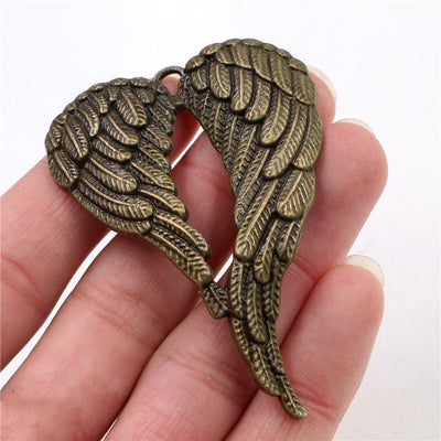 Hand held view of the large folded angel wing pendant showing the front shape and finish