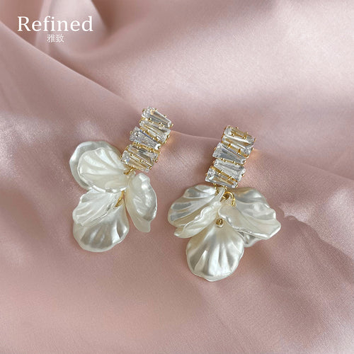 Gold-tone clear-stone-bar translucent-white-petal studs in the first product display.
