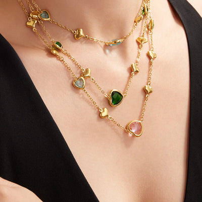 Layered gold heart glass-stone necklaces worn on neckline