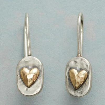 Two-tone hammered heart drop earrings on light blue surface