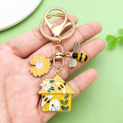 Image 1 showing a hand holding a yellow house shaped keychain.