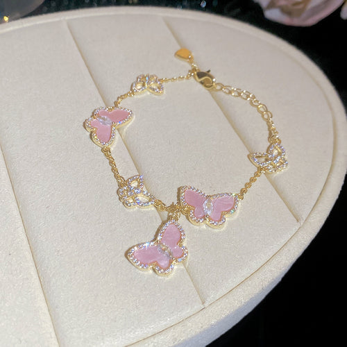 Gold chain bracelet with pink crystal-edged butterfly charms on stand