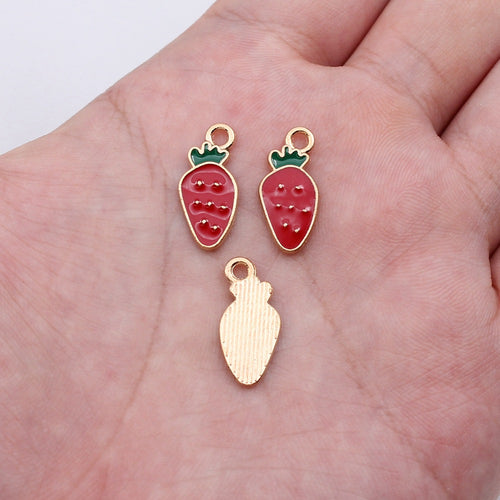Pink strawberry enamel charm shown on a hand for scale