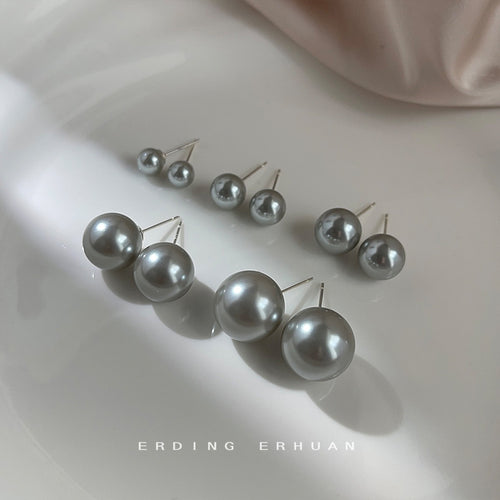 Multiple sizes of grey pearl studs on white plate