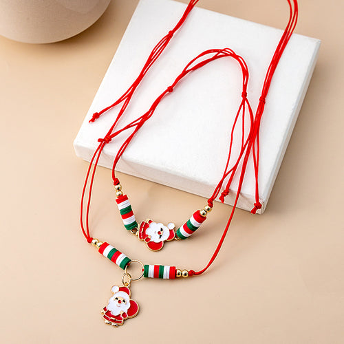 Red cord Santa necklace and bracelet set beside white block