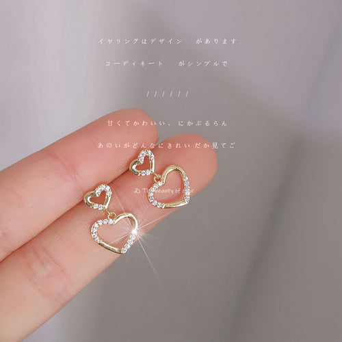 Gold double open heart crystal studs held on fingertips