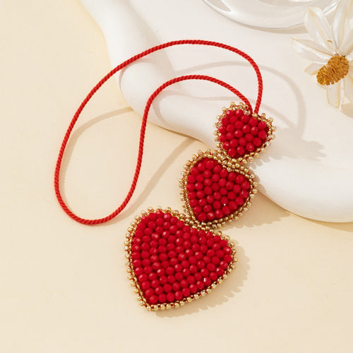 Close-up of red beaded heart trio charm with gold-tone bead trim