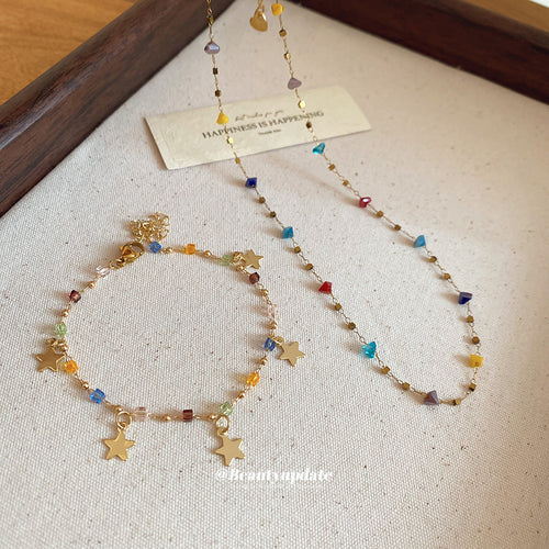 Gold star bracelet and crystal station necklace flat lay on linen tray