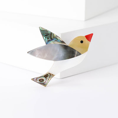 Front view of geometric bird with a red beak and layered iridescent wing and tail inlays