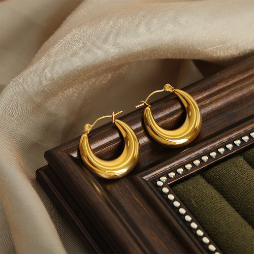 Pair of gold polished U-shape hoops on dark wood tray