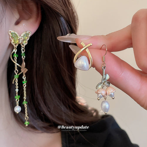 Green butterfly earring worn with pearl wrap and flower drop held