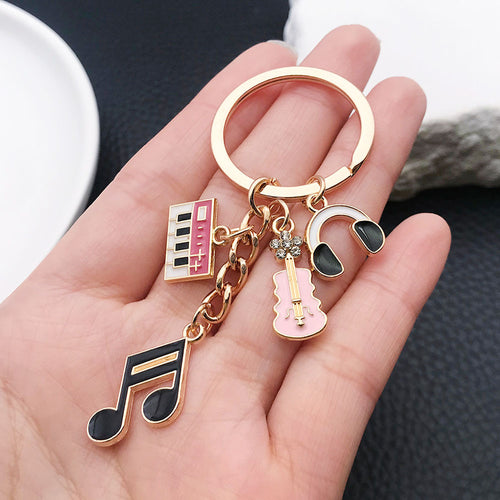 Styled close-up of music note piano violin and headphone charm keychain showing colors and surface details