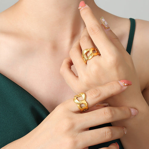 Model wearing gold curb chain link rings on two fingers