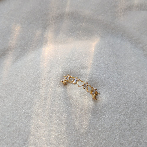 Gold heart and baguette stone open ring on gray fabric