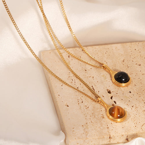 Gold black agate and tiger-eye pendants on stone slab silk backdrop