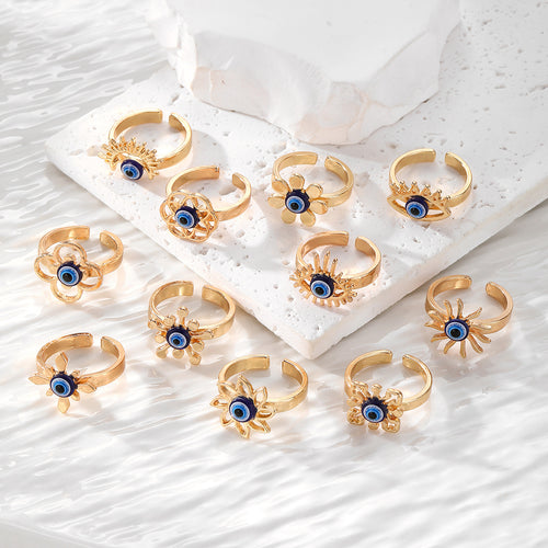 Assorted gold open rings with blue evil eye beads on white stone