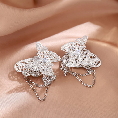 Silver butterfly clip earrings with chain tassels on pink satin