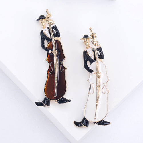 White and amber cello player enamel brooches side by side