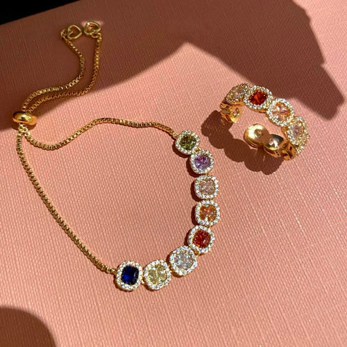 Gold multicolor halo slider bracelet and open ring on pink surface