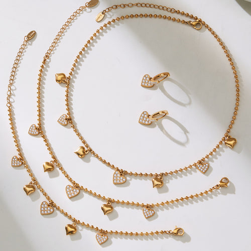 Gold heart charm necklace bracelet and earrings flat lay