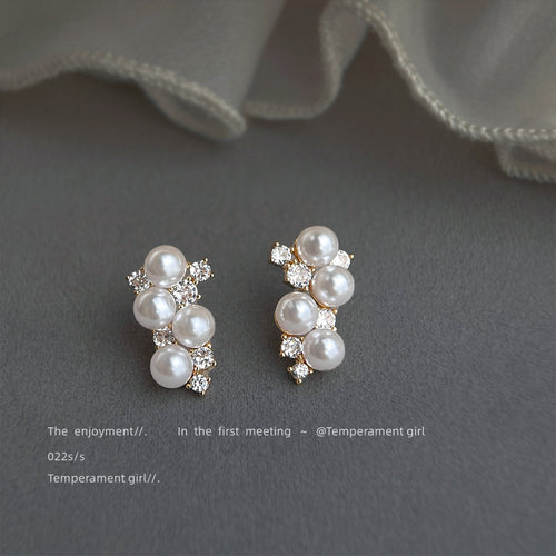Gold four pearl clear stone cluster earrings on grey fabric
