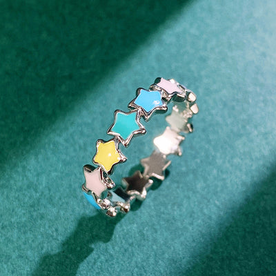 Silver multicolor enamel star band ring on teal fabric top view