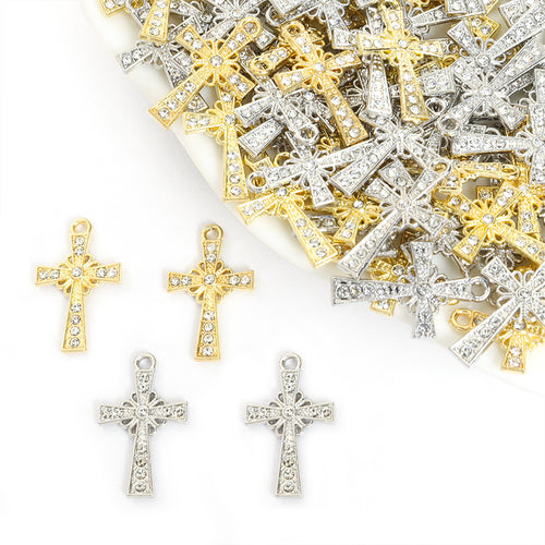 Assorted rhinestone cross charms arranged beside a tray