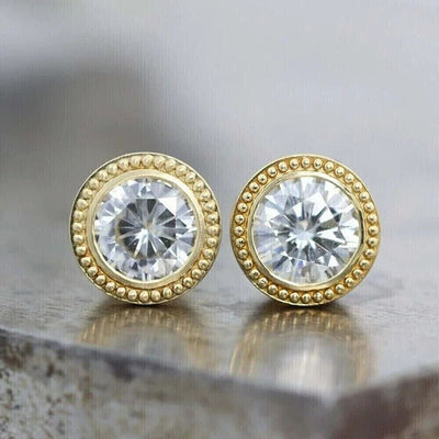 Gold beaded bezel clear CZ stud pair angled on mottled surface