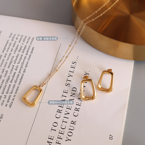 Flat lay gold square pendant necklace and matching studs on book