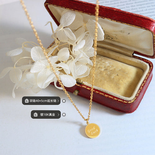 Gold Good Luck disc necklace on table with length plating labels