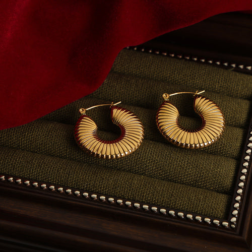 Pair of gold ribbed fan hoops on green jewelry tray
