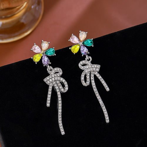 Multicolor flower crystal bow drop earrings on black velvet