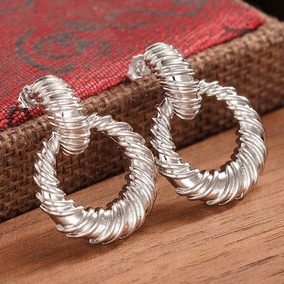 Silver twisted rope round circle drop stud earrings on wood and red
