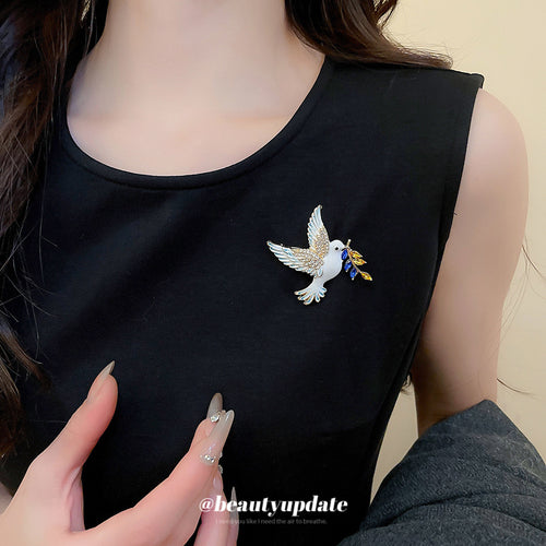 White enamel dove brooch with olive branch pinned on black top