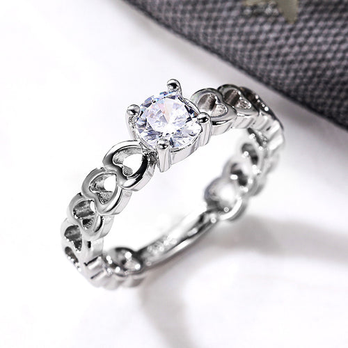 Side angle silver hollow heart band CZ ring on white surface